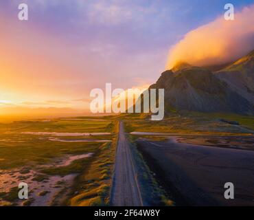 Gravel road at sunset with Vestrahorn mountain in the background, Iceland Stock Photo