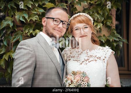 Smiling bridal couple in front of green foliage Stock Photo