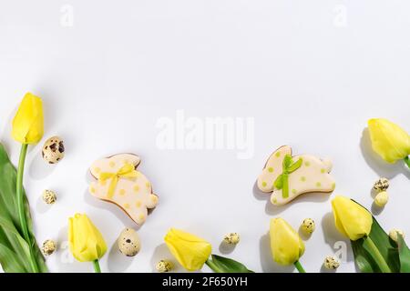 Easter greeting card with tulip flowers, gingerbread cookies bunny and quail eggs on white background Stock Photo