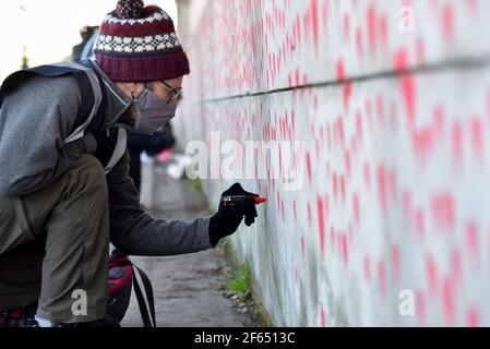 Westminster, London, UK. 30th Mar 2021. People work on the National Covid Memorial Wall opposite the Houses of Parliament. The wall is a being created by families and friends of those who have died. Credit: Matthew Chattle/Alamy Live News