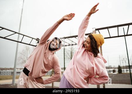 positive african american couple doing side bend exercise outdoors Stock Photo