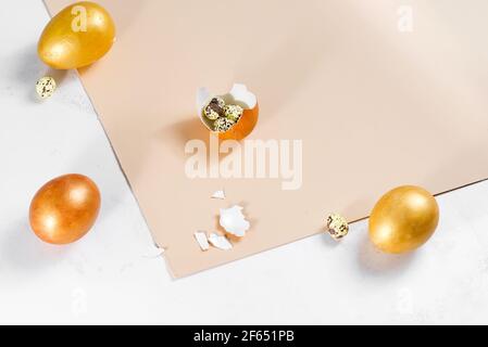 Scattered gold eggs, shell on pastel beige background. Concept of easter, priceless ideas, business investment, or breakfast Stock Photo