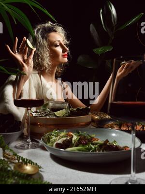 Young blonde woman in evening gown with deep neckline and fur sitting in seafood restaurant on a date Stock Photo
