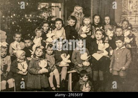 Germany - CIRCA 1940s: Group photo of small kids girls boys and Santa Claus on Christmas New Year Eve party. Vintage archive Art Deco era photography Stock Photo