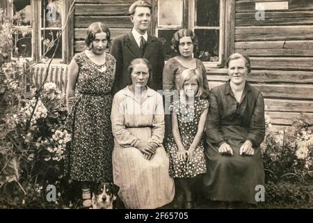 Latvia - CIRCA 1920s: Group portrait shot of five female and man outdoors next to entrance of country house. Vintage Art deco era photo Stock Photo