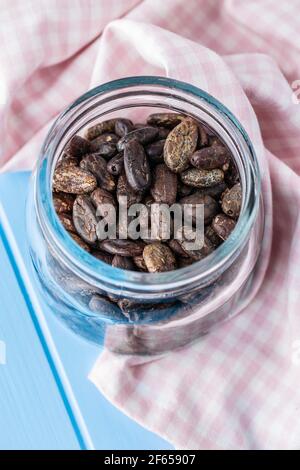 Roasted cocoa beans in jar on blue table. Stock Photo