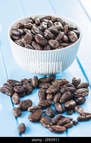 Roasted cocoa beans on blue table Stock Photo