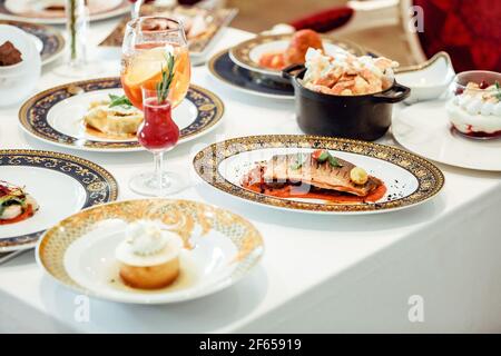 An assortment of dishes and desserts with drinks on a table Stock Photo