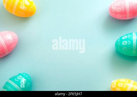 Happy Easter concept with a dyed eggs surrounding the center of the image creating a border around the copy space on baby blue background Stock Photo