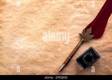 Calligraphy, literature and creative writing concept with a feather quill pen and black ink bottle on old yellowed paper or papyrus with copy space Stock Photo