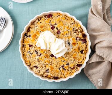 Whole apple and pear crumble with ice cream, streusel. Sweet dessert with stewed fruit topped crisp crumbly mixture served ice cream. Apple cobbler pie in baking dish on tablecloth. Top view Stock Photo