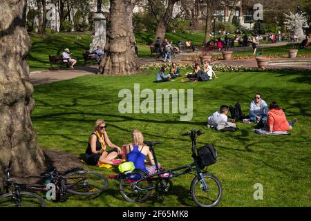 People relax in the sun at the Victoria Embankment Gardens in Central Lodnon. Picture date: Tuesday March 30, 2021. Temperatures in parts of the UK are expected to be significantly warmer this week as families and friends are reunited and sporting activities are allowed to resume in England. Stock Photo