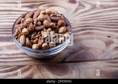 Assorted nuts in glass bowl. Mixed nuts for healthy diet on wooden table. Glass bowl on wooden background. Stock Photo