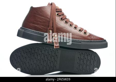 Brown leather sneakers with black rubber sole isolated on white studio background Stock Photo