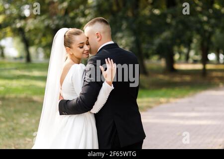 Beautiful bride and groom walking in the park. Stock Photo