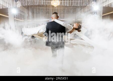 Beautiful bride and handsome groom dancing first dance at the wedding party. Very tender moment Stock Photo