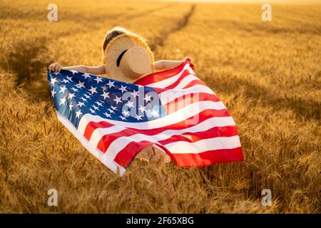 Back view of a girl in white dress wearing an American flag whil Stock Photo