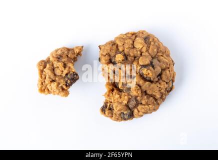 Overhead view of a homemade oatmeal raisin cookie broken in two pieces on a white plate illuminated with natural light. Stock Photo