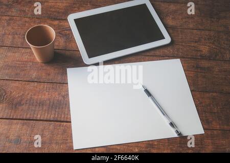 Modern office workplace with tablet pc on the table. On the table there is a tablet and a white sheet of paper with a pen. For a design presentation o Stock Photo