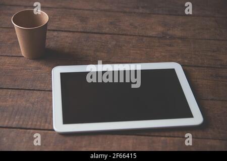 Modern office workspace with tablet pc on the table and a disposable cup of coffee. For a design presentation or portfolio. Stock Photo
