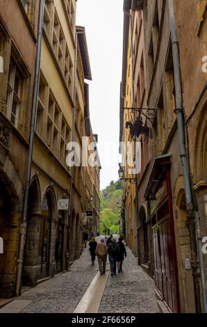 A narrow cobbled street between high, colourful old buildings in Vieux Lyon, France. Stock Photo