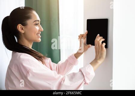 Woman using smart wall home control system Stock Photo