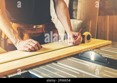 woodworking workshop - carpenter measure and mark the wooden plank for cutting Stock Photo