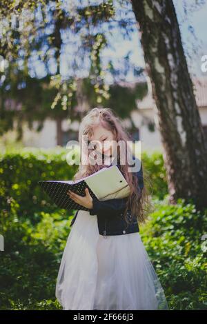Girl in dress holding book in the spring cherry garden Stock Photo