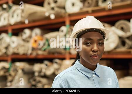 Confident young African woman in hardhat working in a warehouse Stock Photo