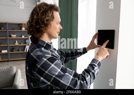 Man Using Smart Home Control System On Digital Tablet Indoors Stock Photo