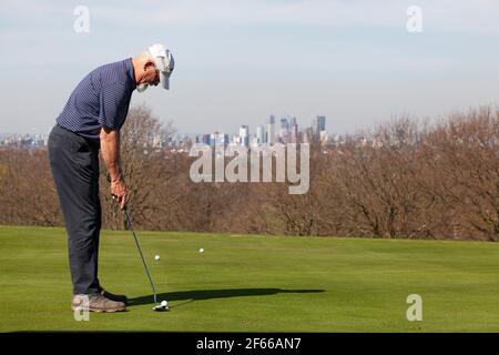 London, UK. March 30 2021: At Dulwich & Sydenham Gold Club, a warm-up on the putting green comes with spectacular views of the London skyline. Warm weather and lockdown easing from coronavirus restrictions now means that outdoor sport is allowed. Credit: Anna Watson/Alamy Live News Stock Photo