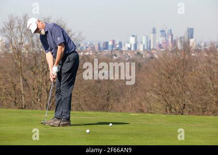 London, UK. March 30 2021: At Dulwich & Sydenham Gold Club, a warm-up on the putting green comes with spectacular views of the London skyline. Warm weather and lockdown easing from coronavirus restrictions now means that outdoor sport is allowed. Credit: Anna Watson/Alamy Live News Stock Photo