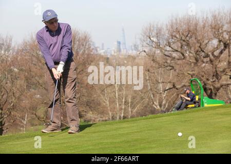 London, UK. March 30 2021: At Dulwich & Sydenham Gold Club, a warm-up on the putting green comes with spectacular views of the London skyline. Warm weather and lockdown easing from coronavirus restrictions now means that outdoor sport is allowed. Credit: Anna Watson/Alamy Live News Stock Photo