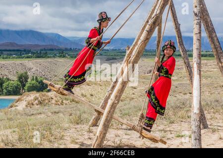 ISSYK KUL, KYRGYZSTAN - JULY 15, 2018: Local girls at a swing at the Ethnofestival Teskey Jeek at the coast of Issyk Kul lake in Kyrgyzstan Stock Photo