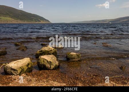 Large Boulders at the water’s edge of Loch Ness Scotland, on a clear windy day Stock Photo