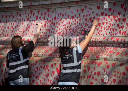 London, UK. 30th Mar, 2021. Volunteers draw hearts on a wall in Lambeth by the River Thames, with each heart representing someone who died during the UK's ongoing coronavirus pandemic. Called The National Covid Memorial Wall, it has been created by the Covid-19 Bereaved Families for Justice and will extend for half a mile by the time it is complete. Credit: Stephen Chung/Alamy Live News Stock Photo