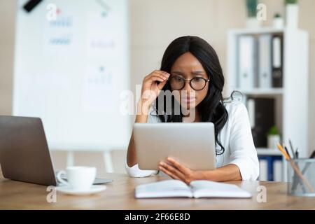 Serious female entrepreneur working on tablet pc at office, participating in webinar or online conference at office Stock Photo
