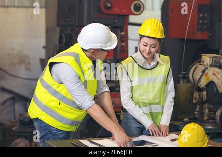 Contractor and engineer with blueprints discuss at a modern construction site, Engineers in mechanical factory reading instructions Stock Photo