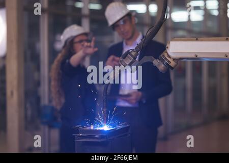 Engineer supervising autonomous producton process industry robot arm in factory Stock Photo