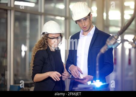 Engineer supervising autonomous producton process industry robot arm in factory Stock Photo