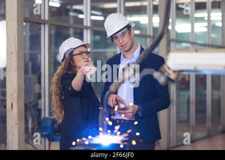 Engineer supervising autonomous producton process industry robot arm in factory Stock Photo