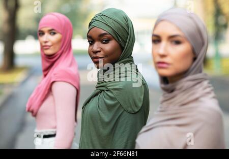 Three diverse millennial ladies wearing hijab posing standing outdoors Stock Photo