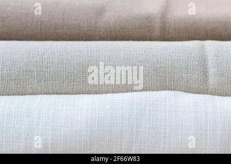 Horizontal textural background of three types of natural linen fabric, rolled up. Selective focus. Closeup view Stock Photo