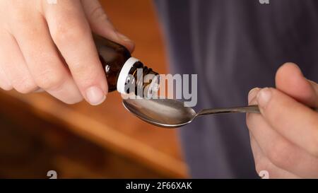 take medicine from a spoon,drip cough syrup closeup. Stock Photo