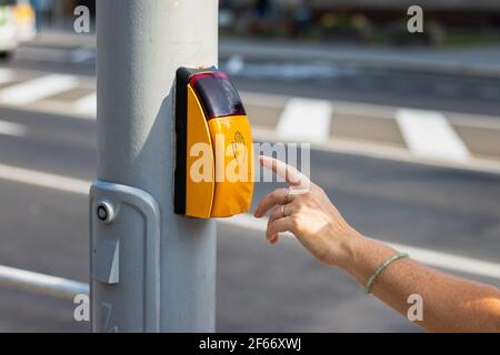 Woman hand pressing crosswalk button to cross the road. Crossing street safely. Walk dont walk signal in city Stock Photo