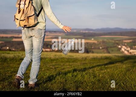 Hiker throwing away plastic bottle in nature. Environmental issues. Irresponsible people and plastic pollution Stock Photo