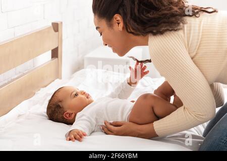 Black Mother Waking Up Her Baby Toddler After Sleep Indoor Stock Photo