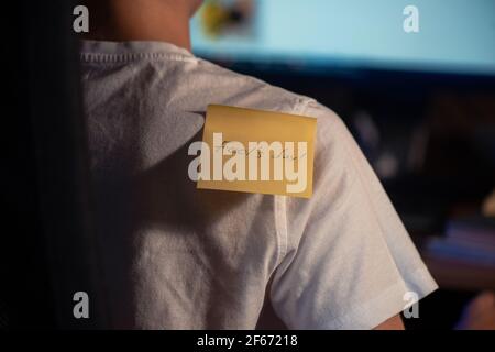 Pasting aprils fools day sticker on young boy shoulder while busy on PC work - concept of April fool day celebration Stock Photo