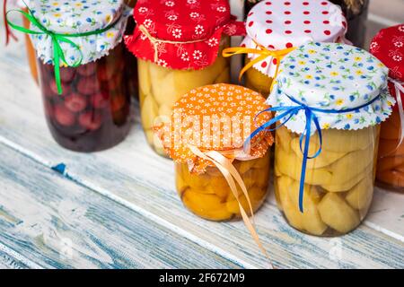 Homemade preserved food, fruit compote in jar. Variety of diferent fruit compotes on white wooden table. Sweet organic food concept Stock Photo