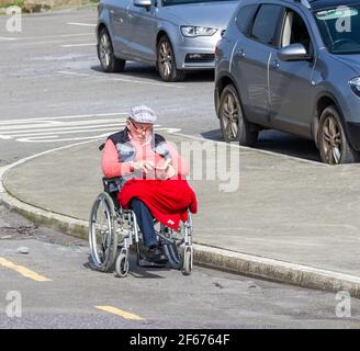 Old gentleman with one leg sat in wheelchair reading a book Stock Photo